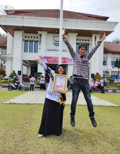 Dr. Sofiawati mengangkat tangan gembira sambil memegang piagam di depan Balaikota Pariaman, di samping rekan yang melompat
