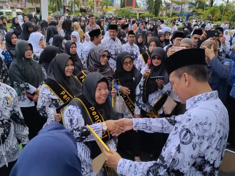 Dr. Sofiawati berselempang Penggiat Literasi berjabat tangan saat menerima penghargaan pada peringatan Hari Guru